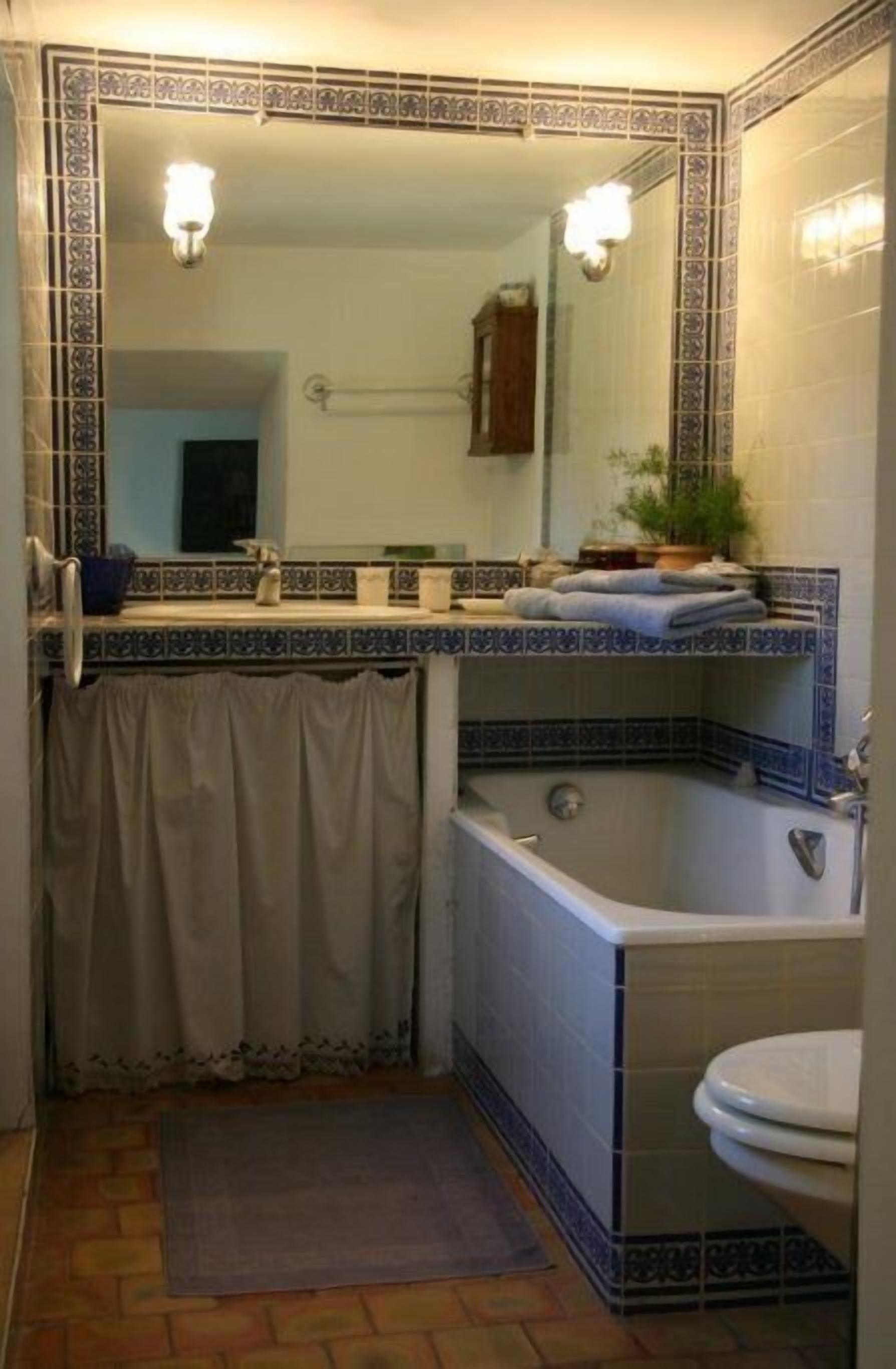 Un baño con bañera, inodoro y lavabo con espejo.