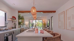 A modern kitchen with a large island, wooden chairs, and pendant lighting. - Casa Azalea in Garcia Ginerés near Downtown (Merida)