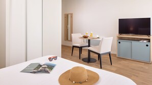 Una habitación de hotel moderna con zona de comedor, televisión y estantería.