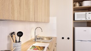 Una cocina con armarios de madera, un fregadero de acero inoxidable, un microondas y un refrigerador Linke.