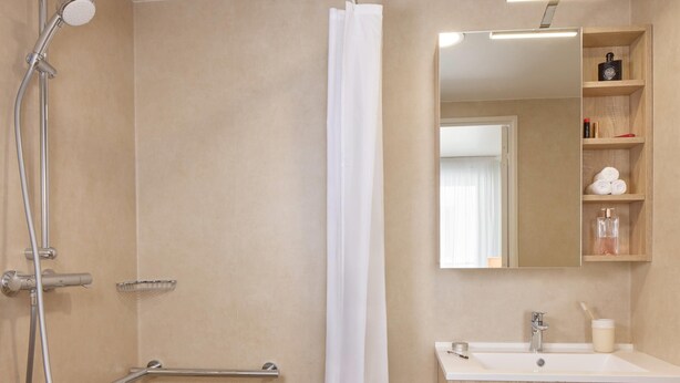 Un baño moderno con ducha, lavabo y espejo.