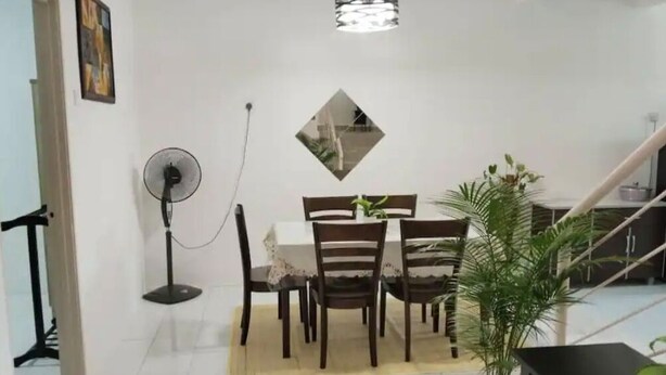 A dining area with a table and chairs, a standing fan, a potted plant, and a staircase in the background. - 
TSA Yasmin House, Kuah, Langkawi, Kedah Malaysia (Langkawi)