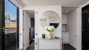 A modern interior with a glass console table, a round mirror, and a vase of white flowers. - Your Apartment - Tower of London (London)