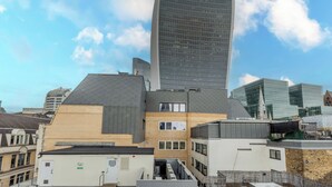 A modern building with a curved glass facade, surrounded by other buildings with varied architectural styles. - Your Apartment - Tower of London (London)