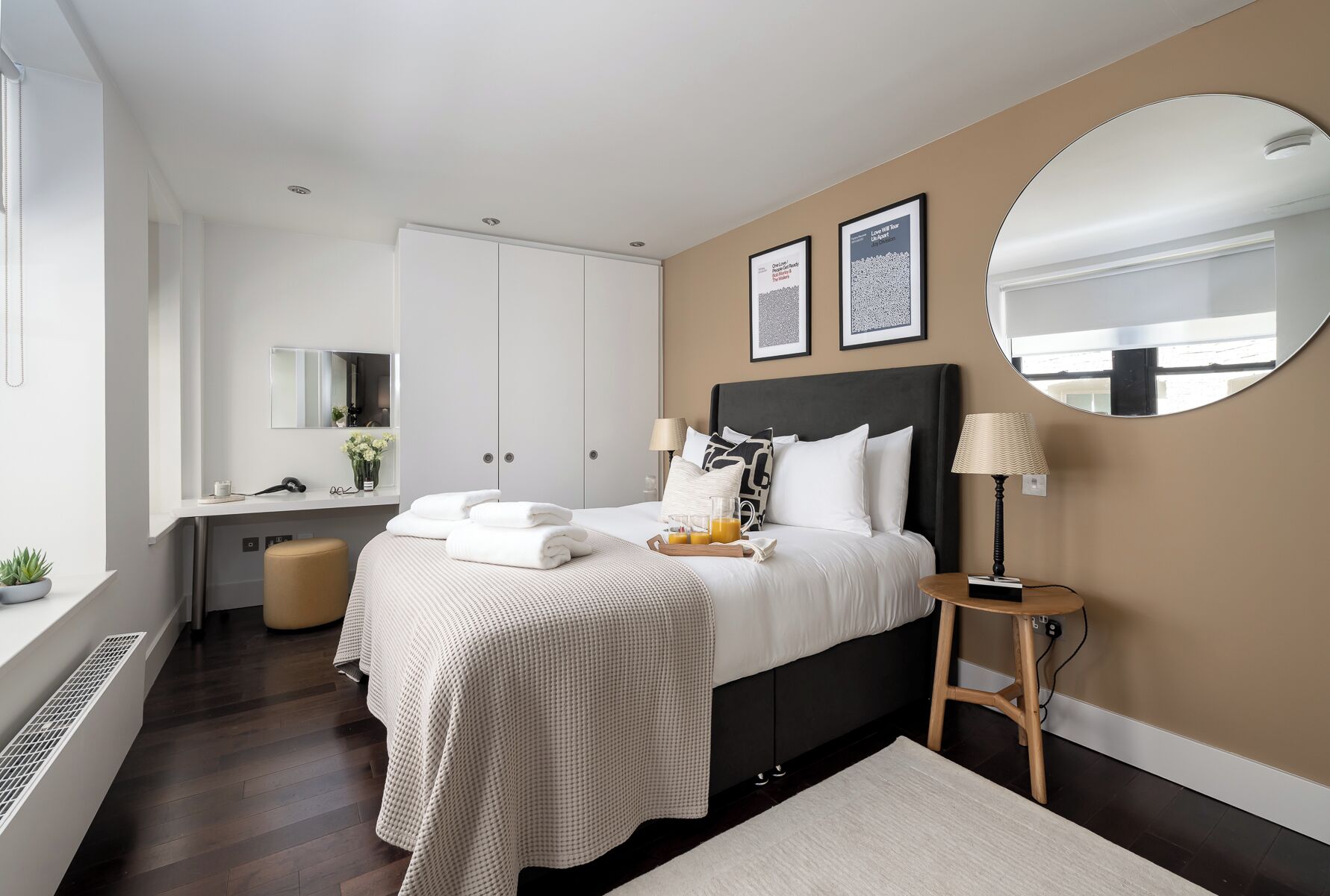 Ein modernes Hotelzimmer mit einem großen Bett, Nachttischen, einem Spiegel und einem Fenster.