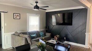 A modern living room with a sofa, a dining table, and a ceiling fan. - Mimosa house (Goldsboro)