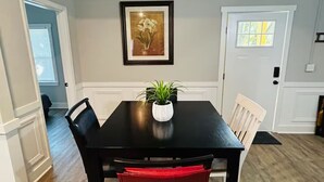 A dining area with a black table, white chairs, and a potted plant. - Mimosa house (Goldsboro)