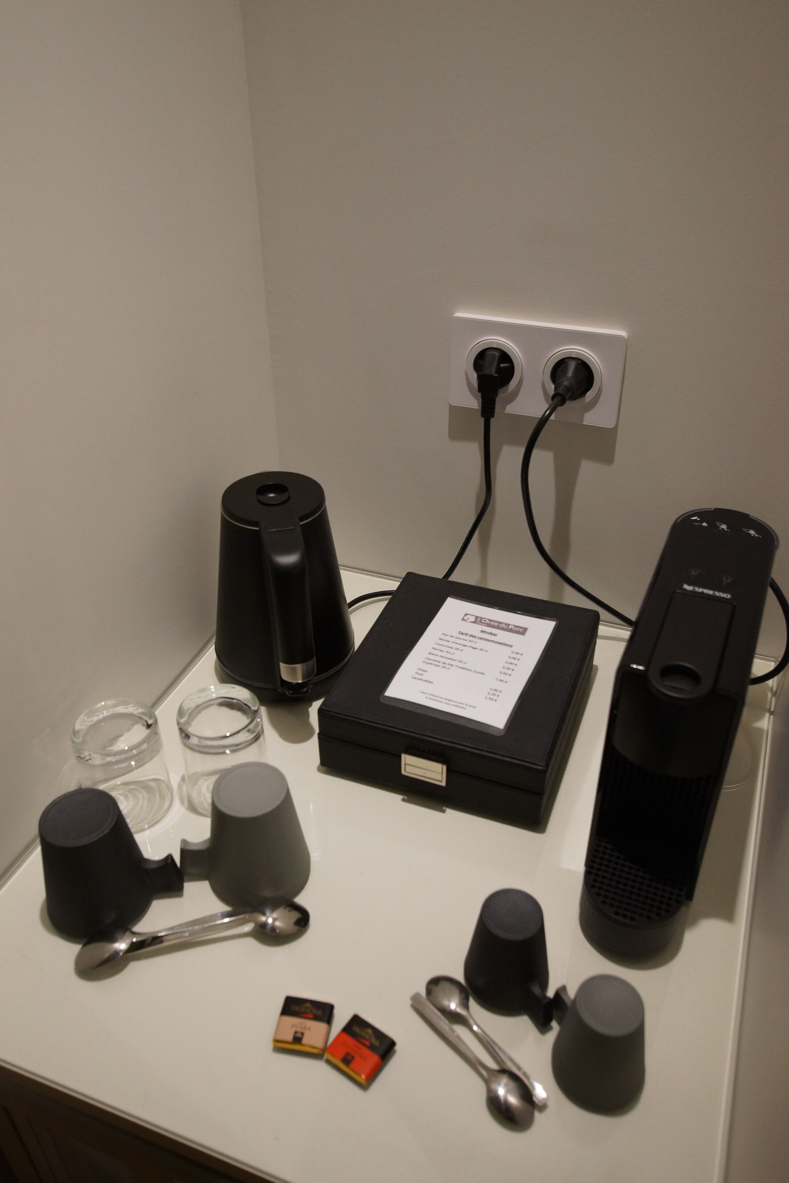 Une table avec une machine à café, une boîte et divers gobelets et cuillères.