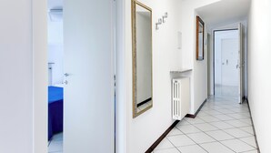 A hallway with white walls, a radiator, and a door leading to a bathroom with a blue bathtub. - Three-room flat Apartment Scola 21 (Gabicce Mare)