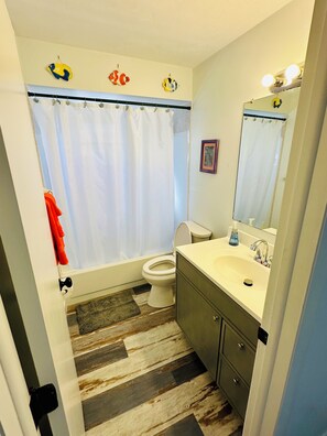 A bathroom with a bathtub, toilet, sink, and a mirror.