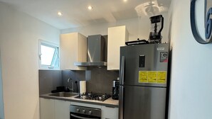 Une cuisine compacte équipée d’une cuisinière à gaz, d’un four, d’un réfrigérateur en acier inoxydable et d’une fenêtre offrant une vue agréable.