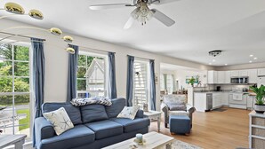 A modern living room with a sofa, coffee table, and a view of the kitchen. - Spacious 4-bedroom Single home in Ocean View with large outdoor spaces and Pool! (Ocean View)