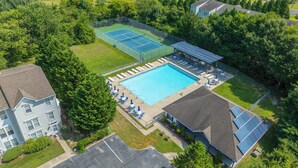 A residential area with a swimming pool, tennis courts, and solar panels. - Spacious 4-bedroom Single home in Ocean View with large outdoor spaces and Pool! (Ocean View)