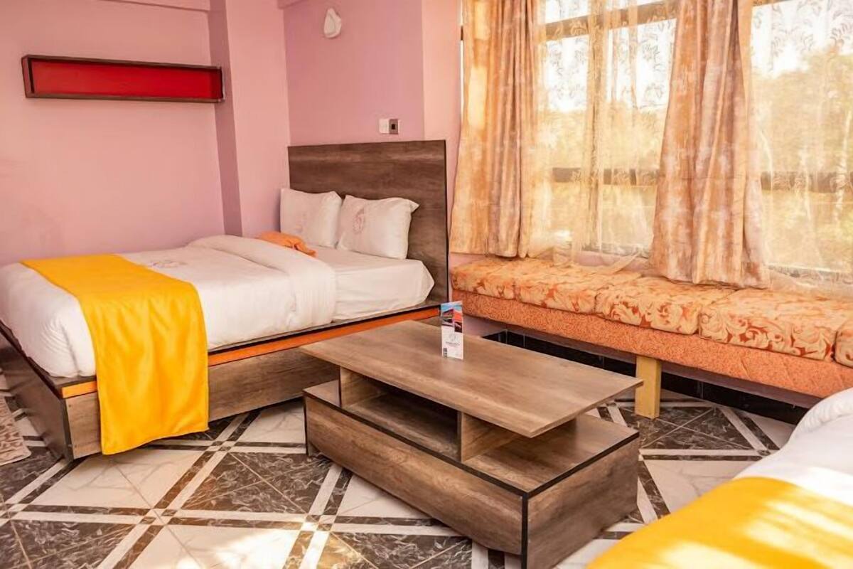 Una habitación de hotel con una cama, un banco y una mesita.