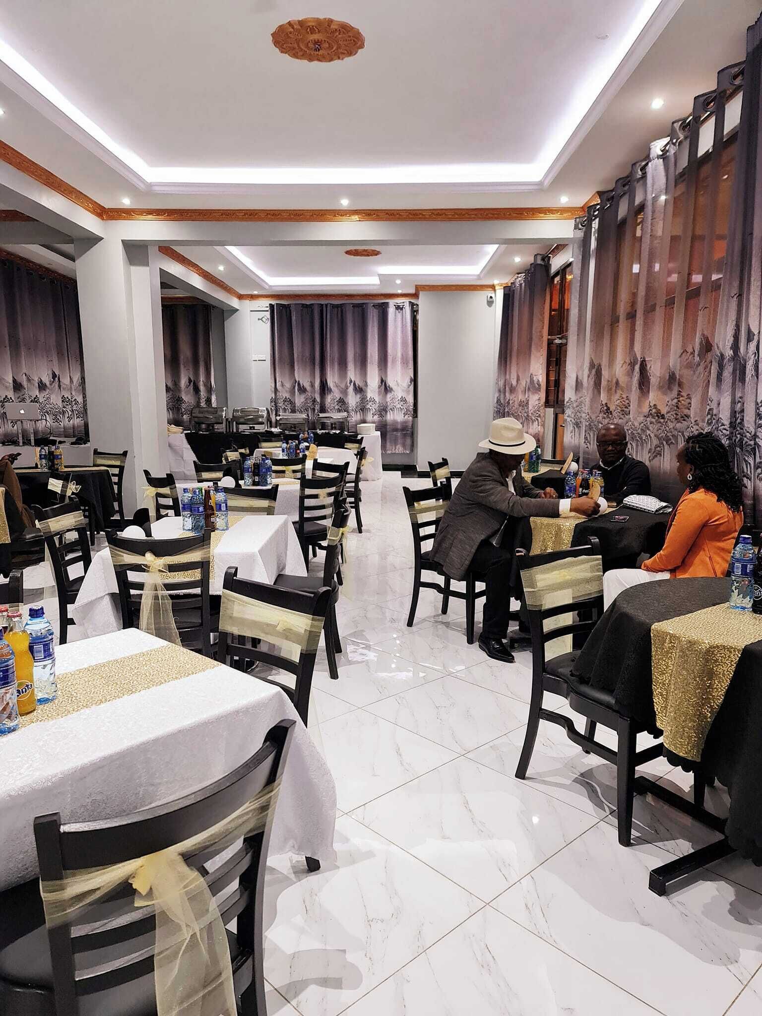 A restaurant with multiple tables and chairs, a tiled floor, and a ceiling with recessed lighting.