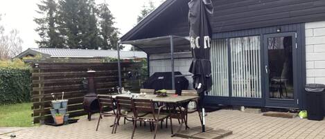 A patio with a table and chairs, a barbecue grill, and a covered area with an umbrella.