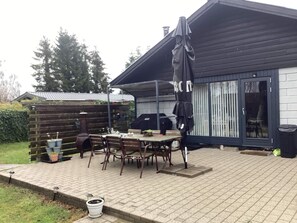 A patio with a table and chairs, a barbecue grill, and a covered area with an umbrella. - 7 Person Holiday Home in Vaeggerlose (Vaeggerlose)