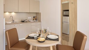 Une cuisine compacte dotée d’appareils électroménagers modernes, une table à manger pour deux personnes et un petit réfrigérateur.