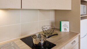 Une cuisine avec une casserole sur la cuisinière, un panier en fil de fer et un livre de recettes sur le plan de travail.