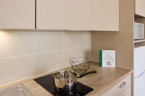 Une cuisine avec une casserole sur la cuisinière, un panier en fil de fer et un livre de recettes sur le plan de travail.