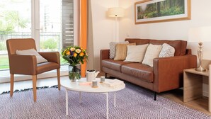 Un salon avec un canapé en cuir marron, une table basse blanche, un fauteuil marron et un vase rempli de fleurs.