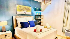 Een slaapkamer met een bed, nachtkastjes, een lamp, een plank met decoratieve objecten, en een schilderij aan de muur.