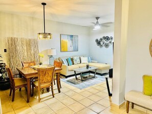 A living room with a dining table, chairs, a sofa, and a coffee table.