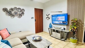 Een woonkamer met een bank, salontafel, televisie en decoratieve voorwerpen.