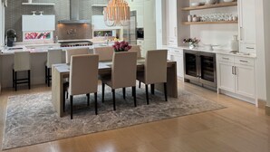 A modern kitchen with a central island, white cabinetry, and a hanging light fixture.