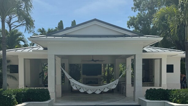 A poolside area with a clear view of the pool, a hammock, and a building with columns.