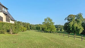 A large house with a sloped roof, surrounded by a well-maintained lawn and a wooden fence. - Apartment with view on the golf of Houlgate (Houlgate)