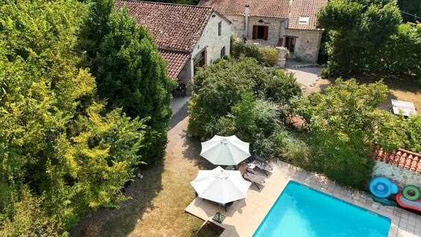 An aerial view of a property with a swimming pool, two umbrellas, and surrounding greenery. - Spacious grange - Domaine de Gargoris (Pont-du-Casse)