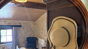 A bedroom with a bed, a chair, a window, and a mirror reflecting the room. - Spacious grange - Domaine de Gargoris (Pont-du-Casse)