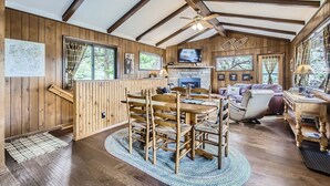 Ein gemütliches Blockhaus-Interieur mit Essbereich, Kamin und Fernseher.
