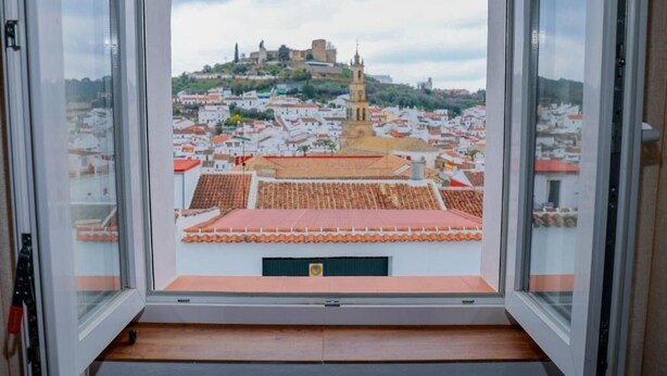 A view from a window overlooking a cityscape with a prominent hill and a tower. - CERRO LUNA HOUSE (Constantina)