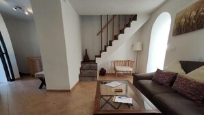 A living room with a sofa, a glass coffee table, a staircase, and a lamp. - CERRO LUNA HOUSE (Constantina)