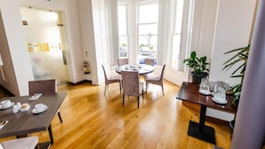 A hotel room with a round dining table, four chairs, a potted plant, and a window with curtains. - Opul Boutique (Douglas)