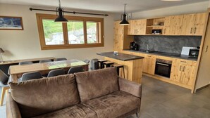 Eine moderne Küche mit Holzausstattung, einer zentralen Kochinsel und einem Essbereich mit braunem Sofa und Stühlen.