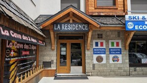 Ein Gebäude mit einem Schild, auf dem „LA RESIDENCE“ steht, sowie zwei kleinere Schilder mit den Aufschriften „MONITEURS“ und „MAESTRI ITALIANI“.
