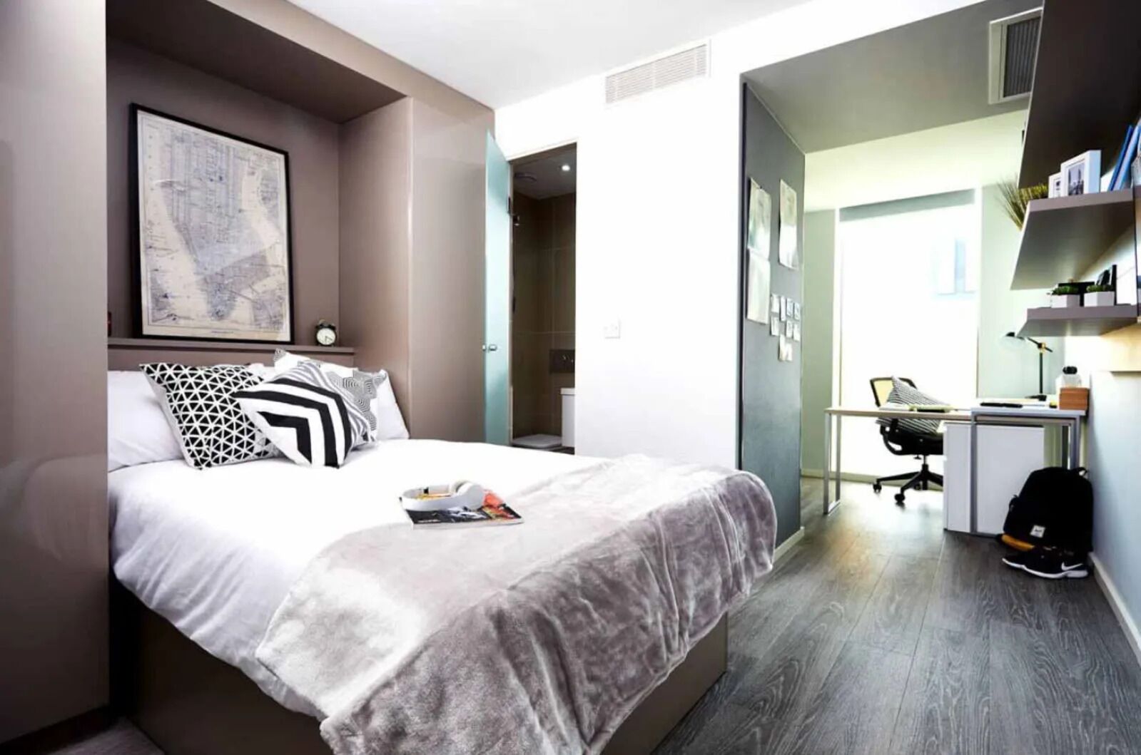 Ett modernt hotellrum med en säng, ett skrivbord och en stol.