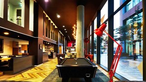 A billiards table with a red lamp, a pool table, and a bar area with bookshelves and seating. - Student Only Vita First Street (Manchester)