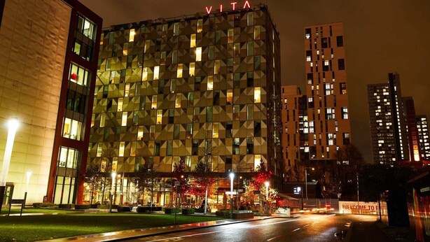 A modern building with a geometric facade and the name "VITA" illuminated at the top. - Student Only Vita First Street (Manchester)