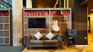 A lobby with a leather sofa, a BINGO wall, and a reception desk. - Student Only Vita First Street (Manchester)