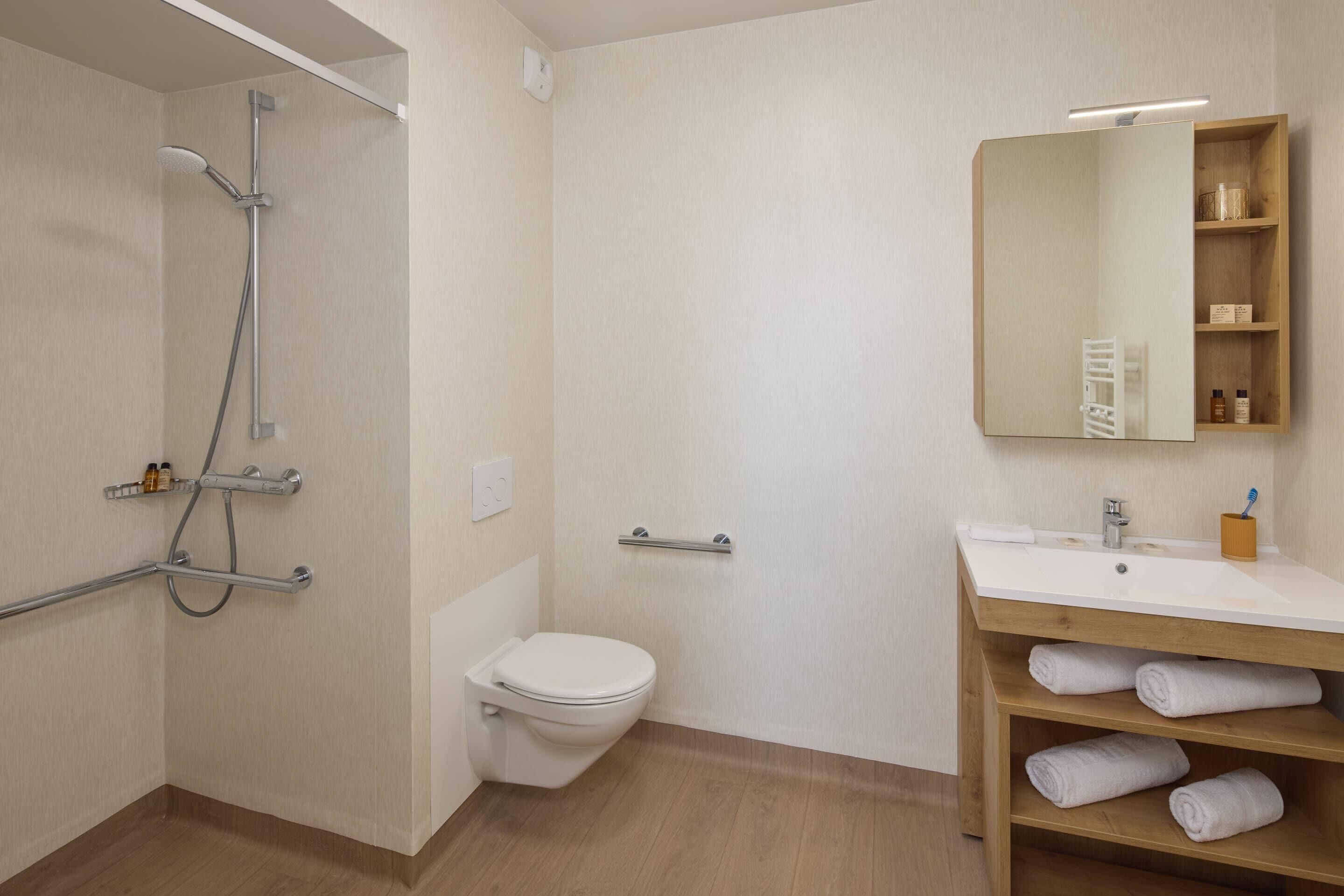 Un baño con ducha, inodoro, lavamanos y espejo.
