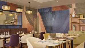 Een modern restaurantinterieur met geometrische wanddecoratie, hanglampen en net geordende tafels en stoelen.