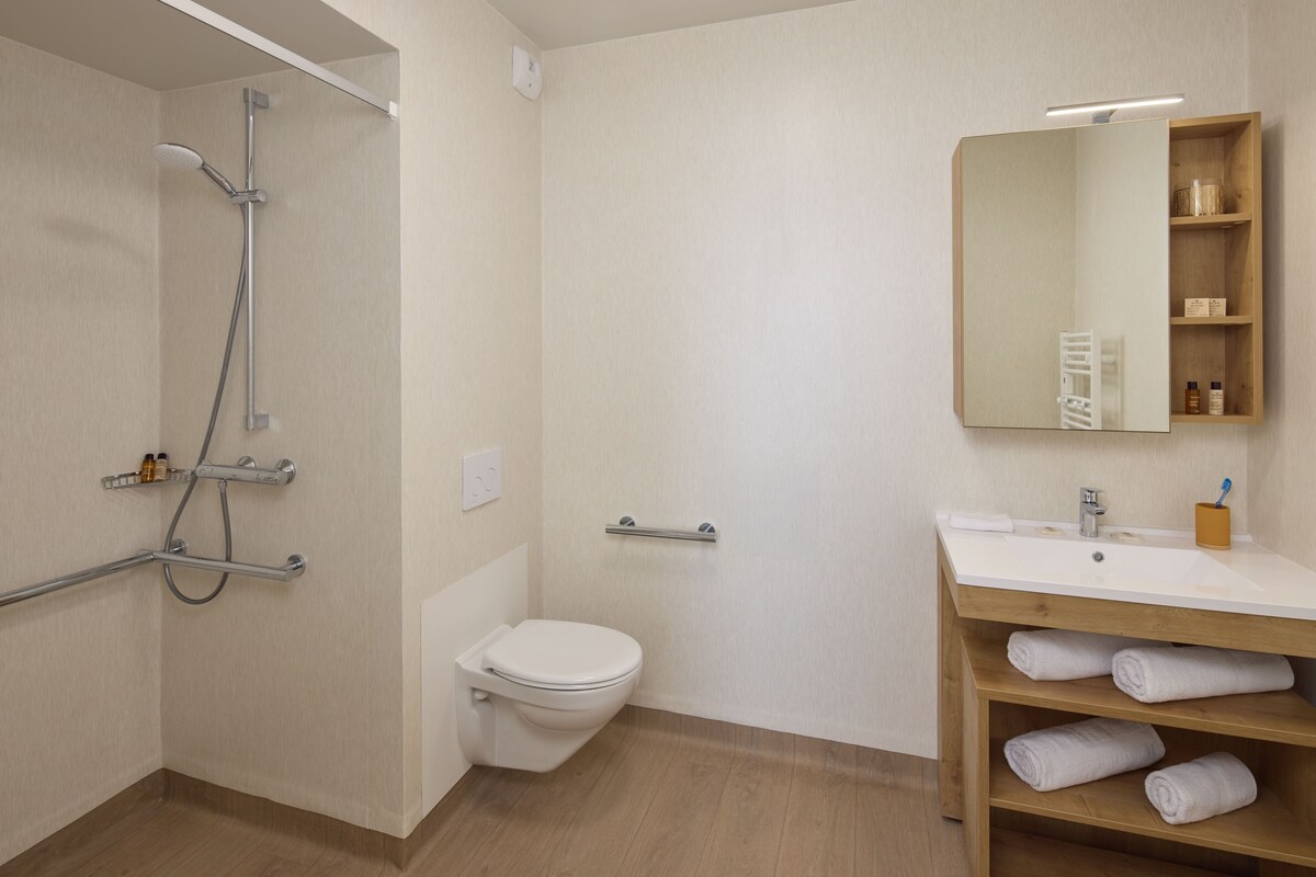 A bathroom with a shower, toilet, sink, and a mirror.