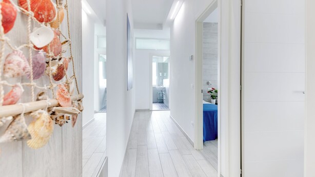 A hallway with a nautical-themed wall decoration, a blue table with a potted plant, and a white door. - Three-room apartment Scola 11 (Gabicce Mare)