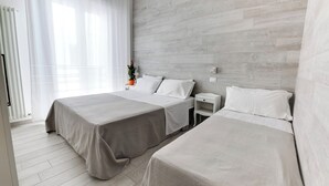 A hotel room with two beds, a wooden headboard, a nightstand, and a potted plant. - Three-room apartment Scola 11 (Gabicce Mare)