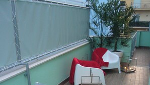 A rooftop terrace with a dining table set with oranges, glasses, and candles. There are chairs and a potted plant. - Three-room apartment Scola 11 (Gabicce Mare)
