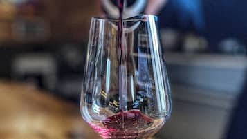 A glass of red wine being poured into a stemmed glass.